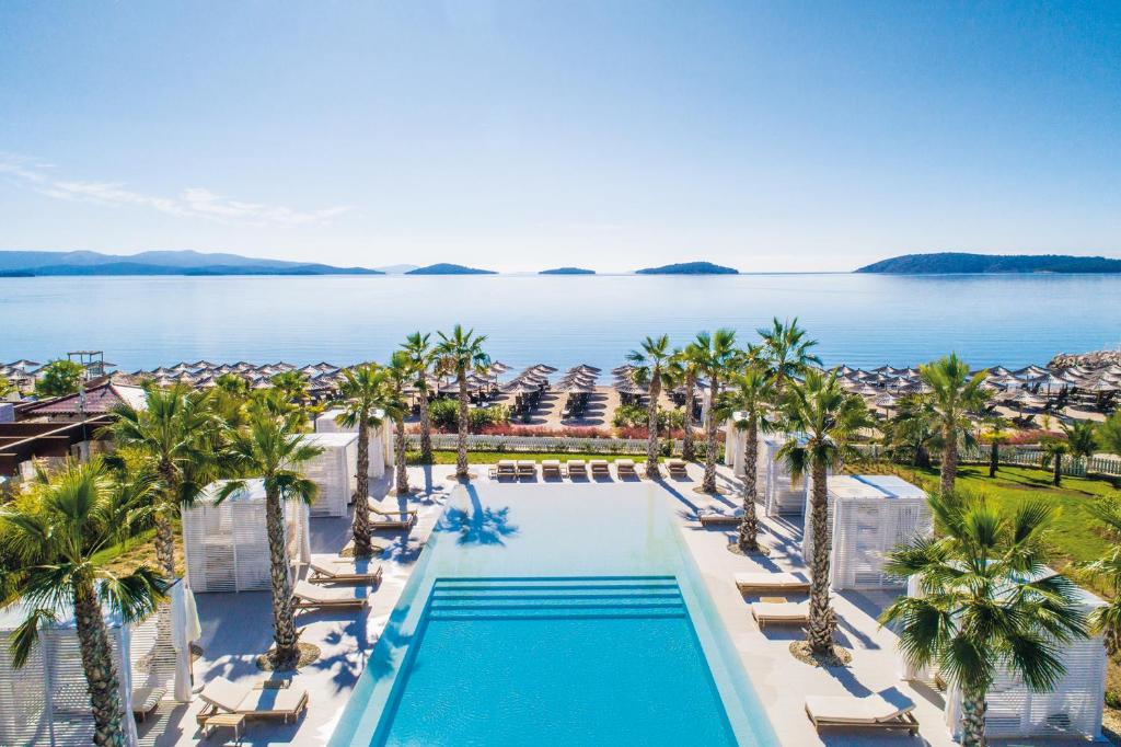 vista aerea su una piscina del resort con palme e sull'oceano di Amadria Park Beach Hotel Jure a Šibenik