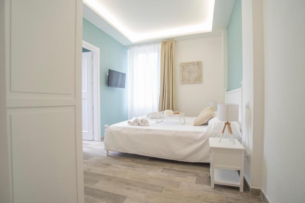 1 dormitorio con 1 cama blanca y paredes azules en Casa Solmes Rooms en Olbia