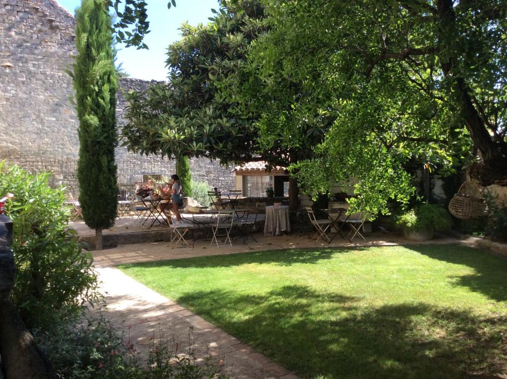 un jardín con mesa, sillas y árboles en Le Posterlon en Caumont-sur-Durance