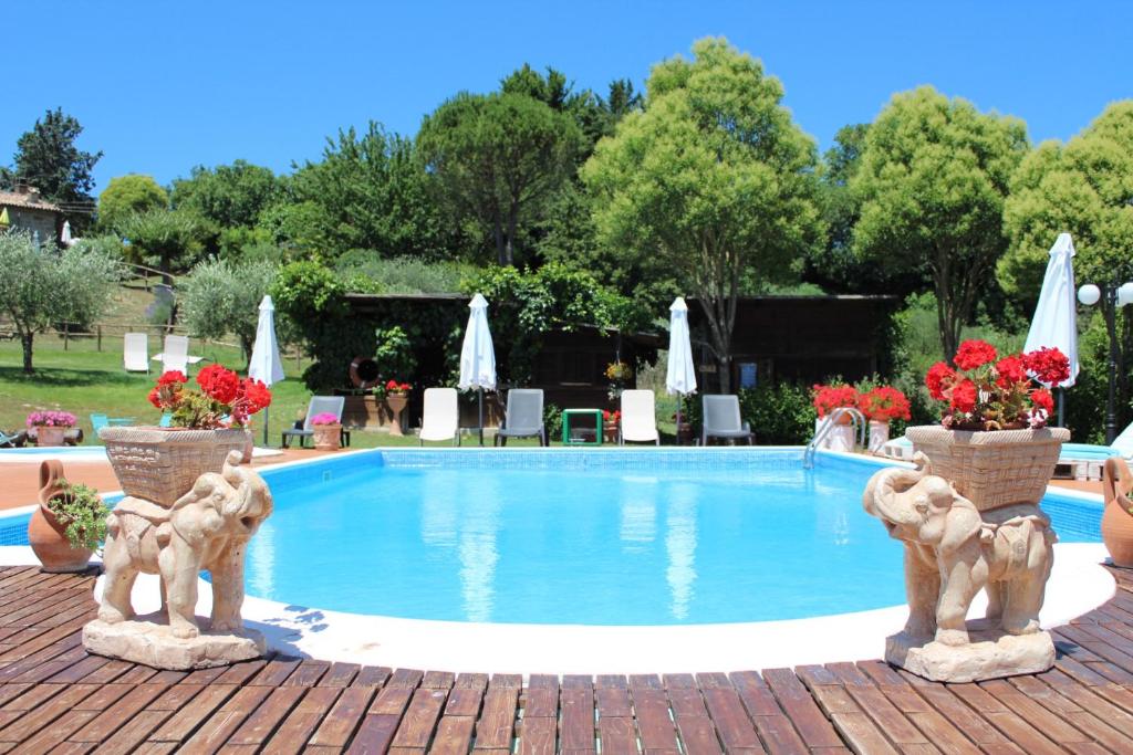 a swimming pool with two statues in front of it at Agriturismo Poggio Paradiso in Mengara