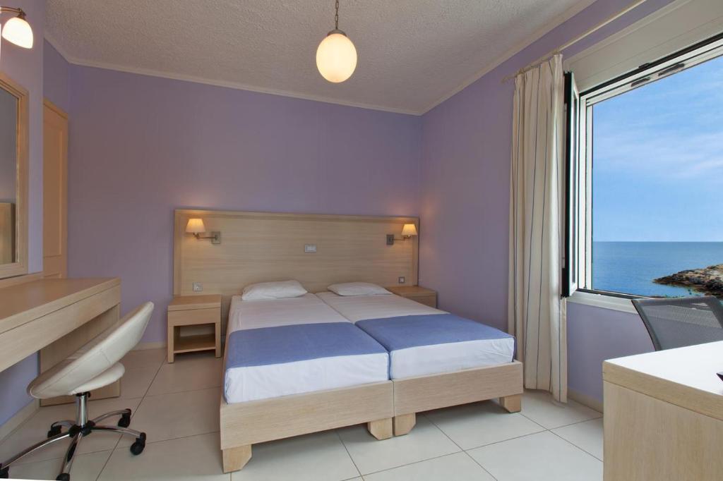 a bedroom with a bed and a view of the ocean at Giorgi's Blue Apartments in Kalathas