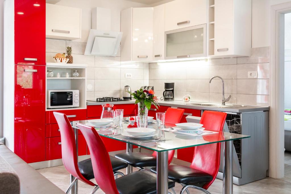 une cuisine rouge avec une table et des chaises rouges dans l'établissement Apartman Gabrijela, à Split