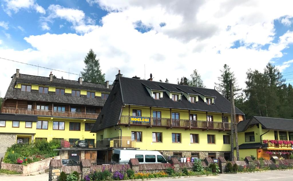 um edifício amarelo com um telhado preto em uKazika em Orawka