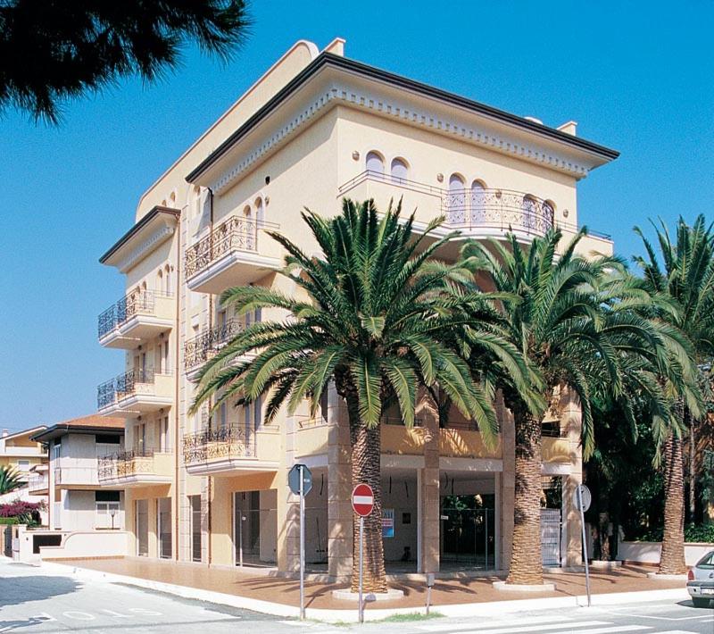 a large building with palm trees in front of it at Residence Le Palme in Alba Adriatica