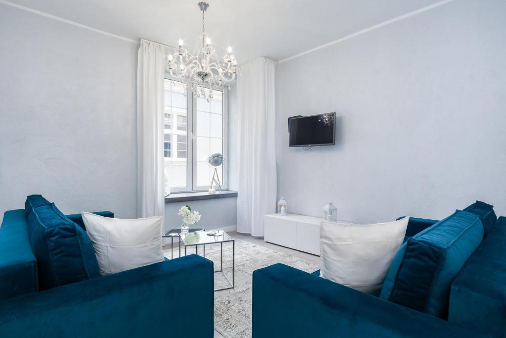 a living room with two blue couches and a tv at Elite Apartments Old Town Suite in Gdańsk