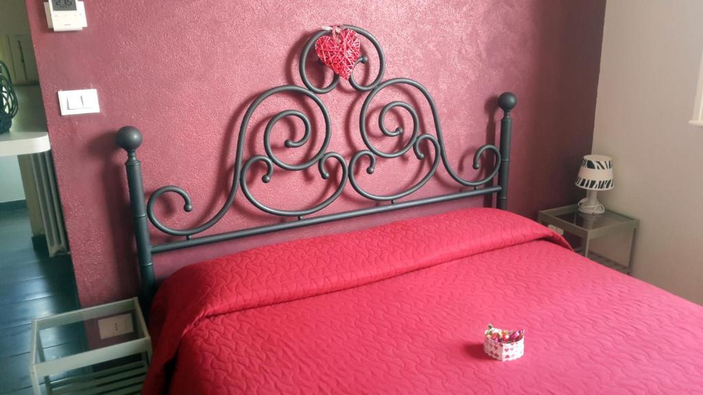a red bed with a red comforter and a pink wall at Mamma Casa Superior in Rimini