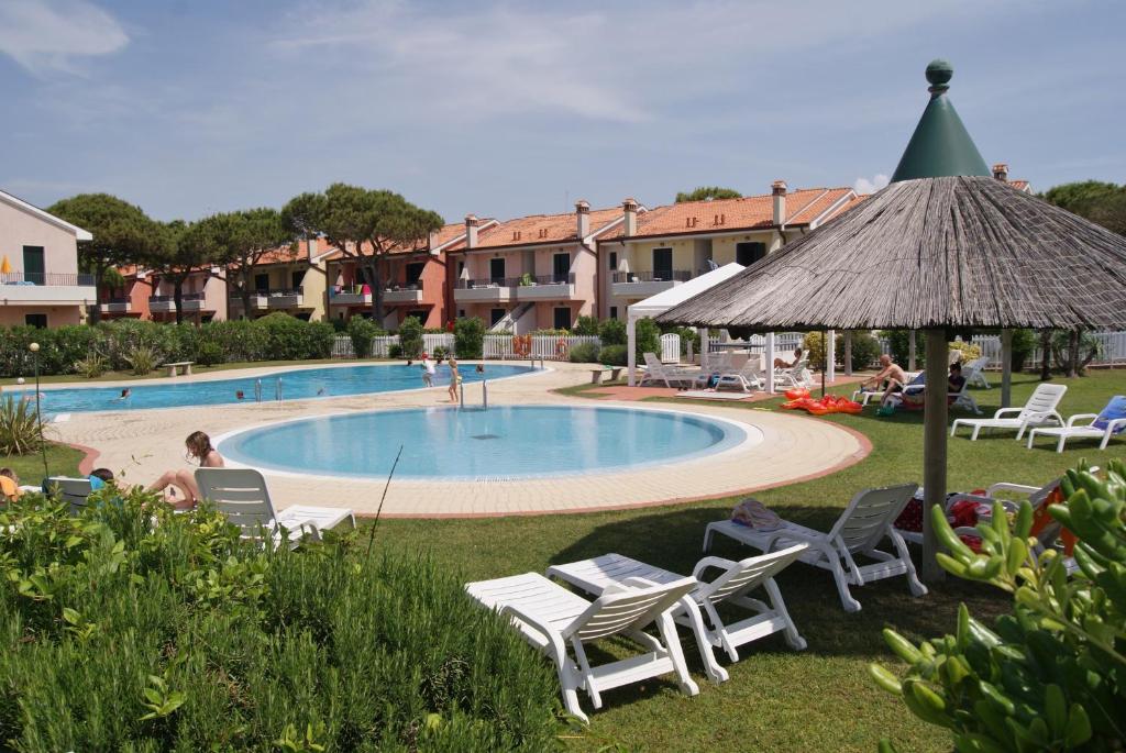 ein Resort mit einem Pool, Stühlen und einem Sonnenschirm in der Unterkunft Appartamenti in Residence Portosole e Residence Tamerici con piscina-Cavallino Treporti in Cavallino-Treporti