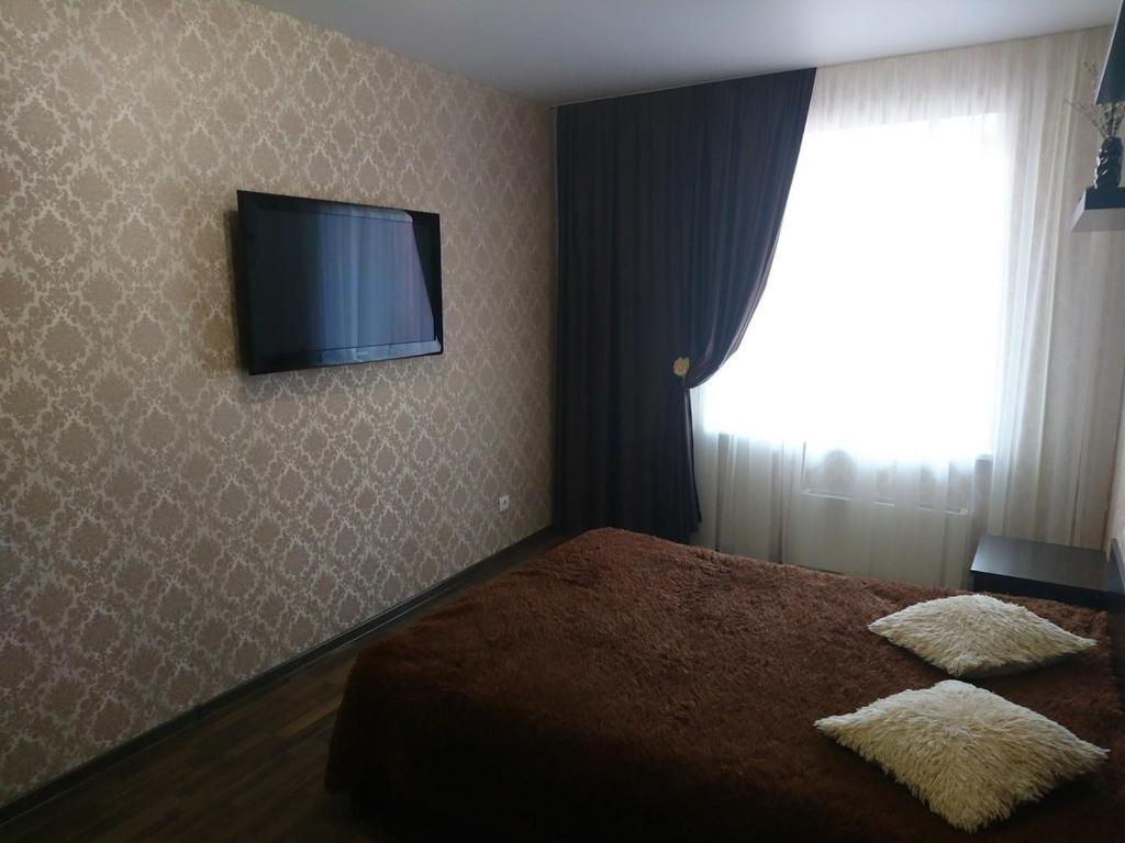 a bedroom with a bed and a television on the wall at Kommunisticheskaya 15-62 in Saransk