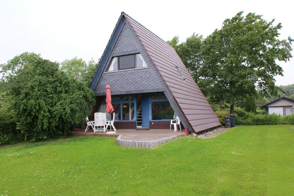 a small house with a gambrel roof on a lawn at Zeltdachhaus mit WLAN in Strandnaehe in Damp