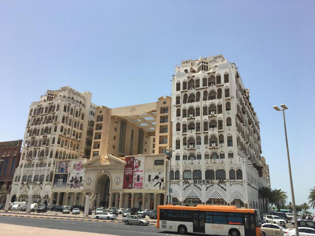 un autobús naranja estacionado frente a un edificio en Kuwait Palace Hotel en Kuwait