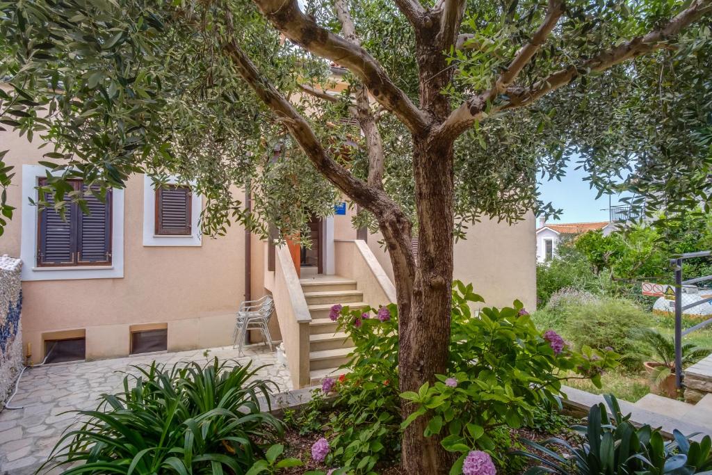 a tree in front of a house with flowers at Filip Apartment in Mali Lošinj