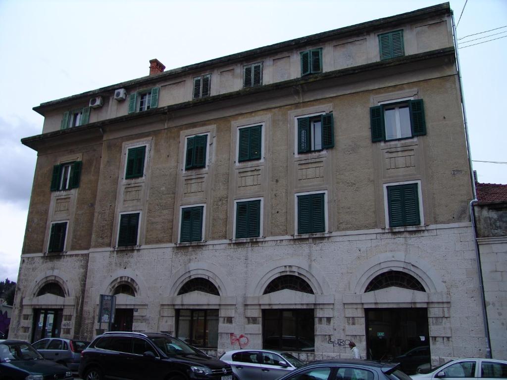 a large brick building with windows and cars parked in front at Rooms Šećer in Split
