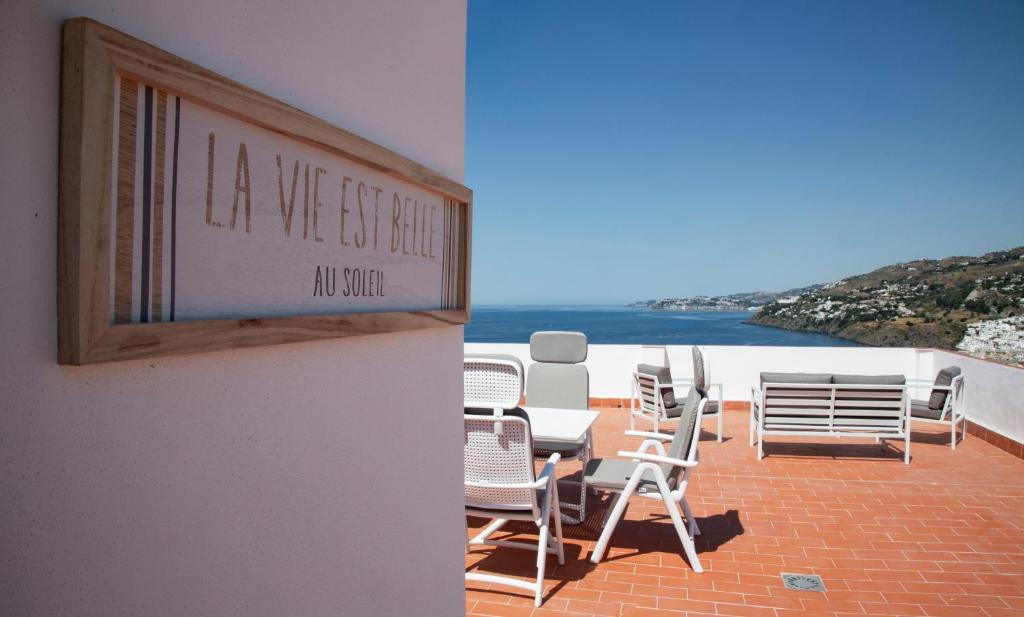 a group of chairs and tables on a patio with the ocean at La Roka in Salobreña