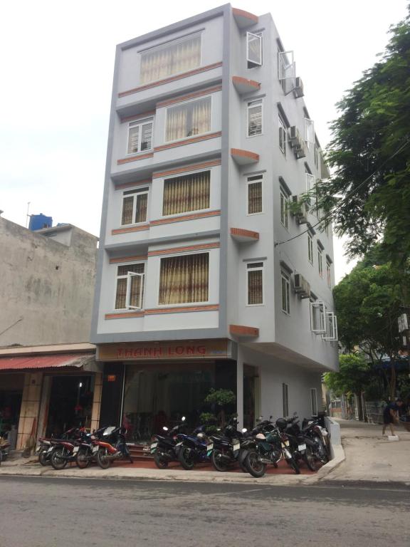 a tall white building with motorcycles parked in front of it at Homestay Thanh Long in Cat Ba