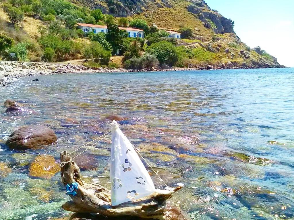 a toy sail boat in the water on a beach at Enalion Apartments in Agios Ioannis Kaspaka