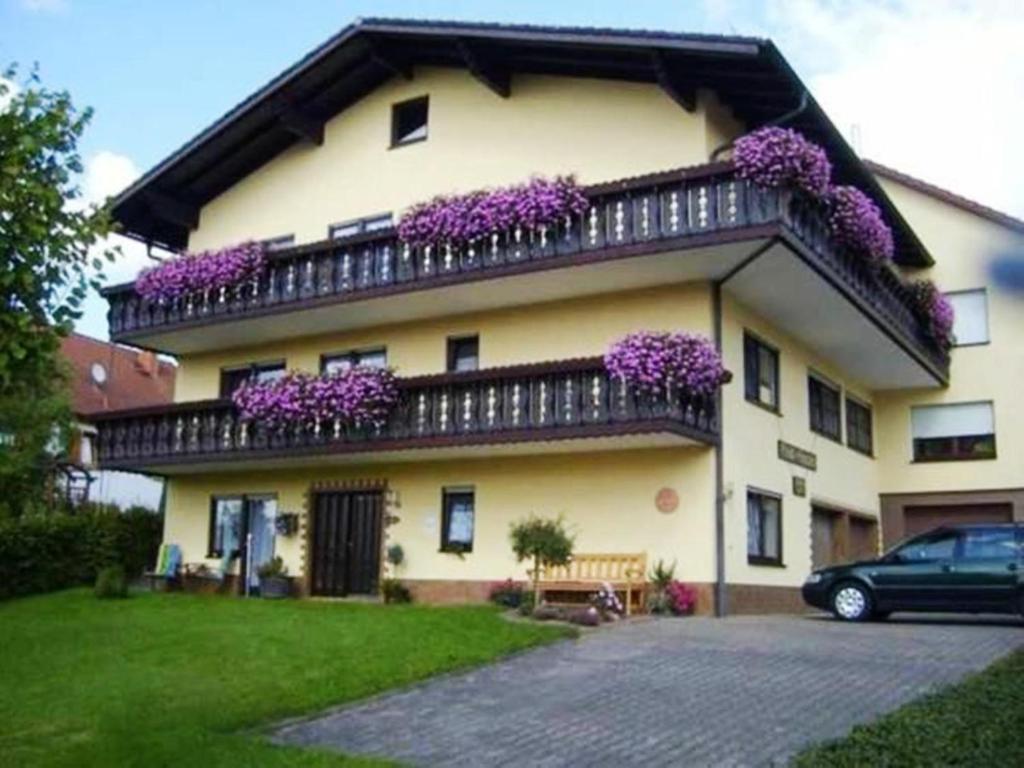 dom z fioletowymi kwiatami na balkonie w obiekcie Ferienwohnung Am Limespfad w mieście Hesselbach
