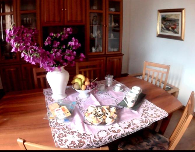 a dining room table with a vase of flowers and fruit at casa andreana in Uri