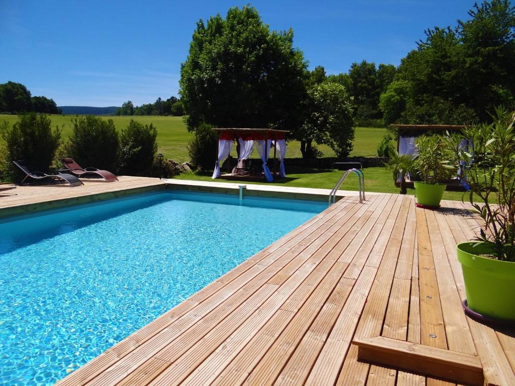 une piscine avec une terrasse en bois et une piscine dans l'établissement La maison de Gilbert, à Chaudes-Aigues