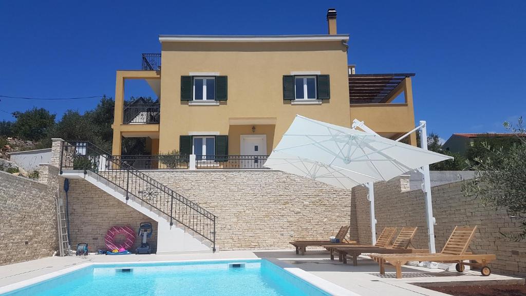 uma casa com piscina e guarda-sol branco em Apartment Azaleja em Sali