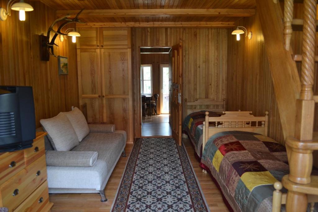 a room with two beds and a couch and a tv at Kotedžas prie pušelių in Nida