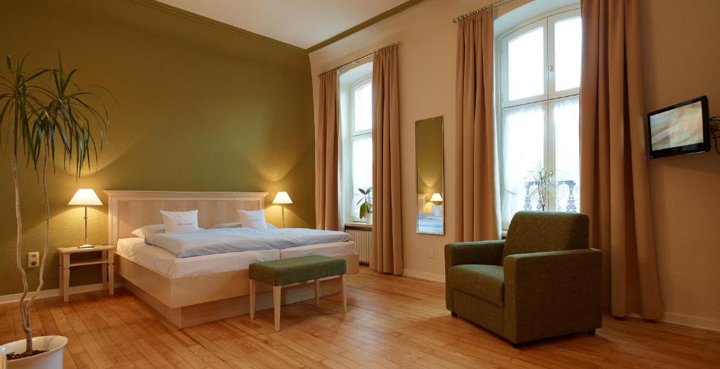 a bedroom with a bed and a chair and windows at Pension Martinerhof in Wintrich