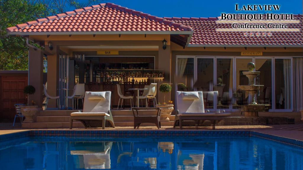 a pool with chairs and a bar next to a house at Lakeview Boutique Hotel & Conference Center in Benoni