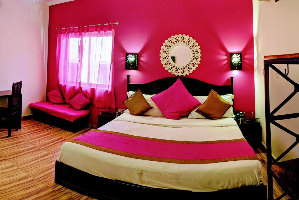 1 dormitorio con 1 cama grande y pared de color rosa en La Casa, en Haridwar