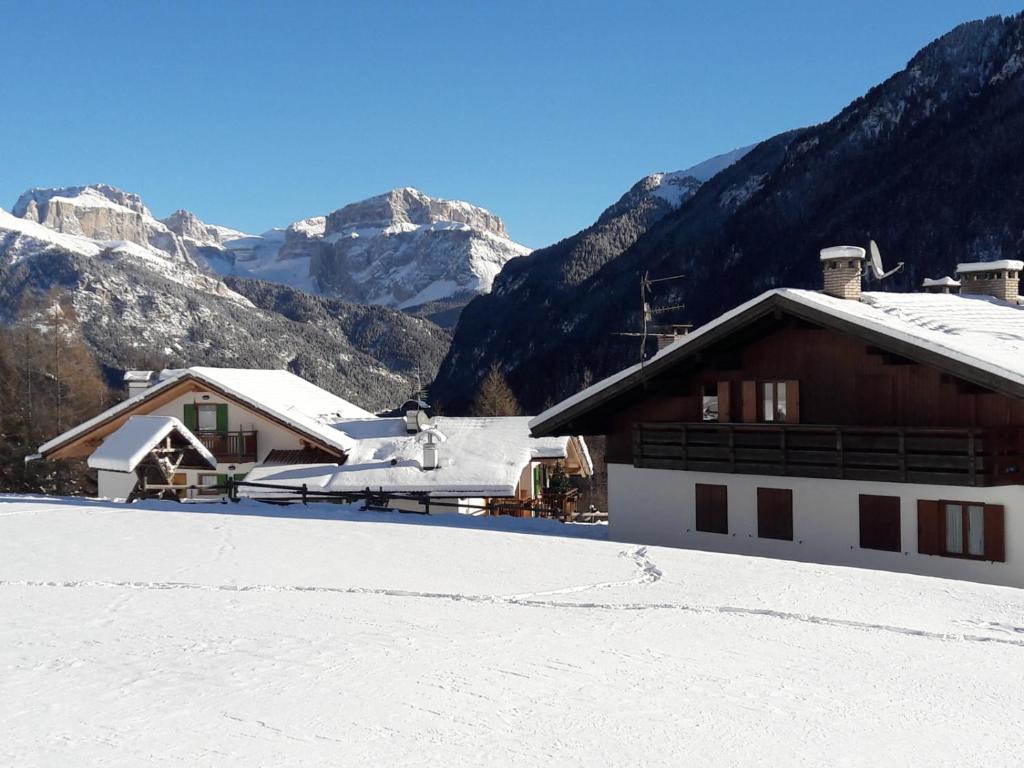 a snow covered building with mountains in the background at Chalet Relax in Pozza di Fassa