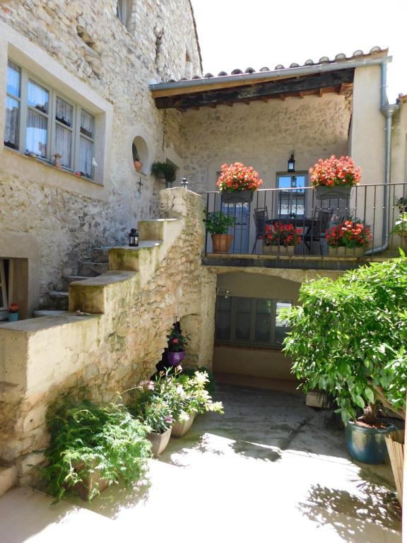 una casa de piedra con flores en el balcón en La Maison Jules Goux, en Mirmande