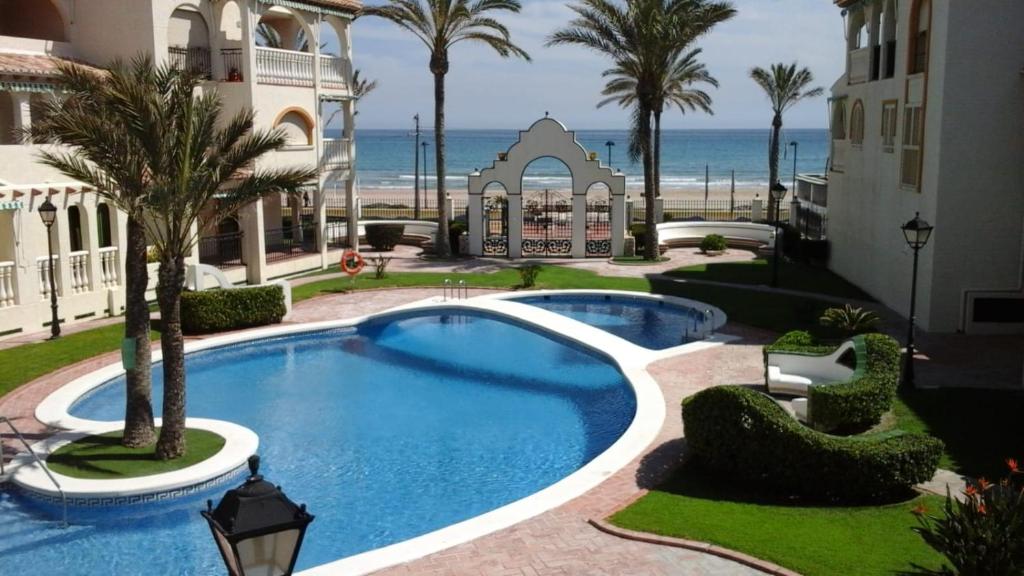 a swimming pool in front of a building with the beach at Playa Muchavista lovely ground floor apartment in El Campello