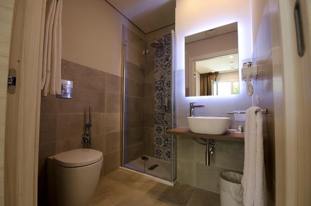 a bathroom with a toilet and a sink and a mirror at Hermes Hotel in San Vito lo Capo
