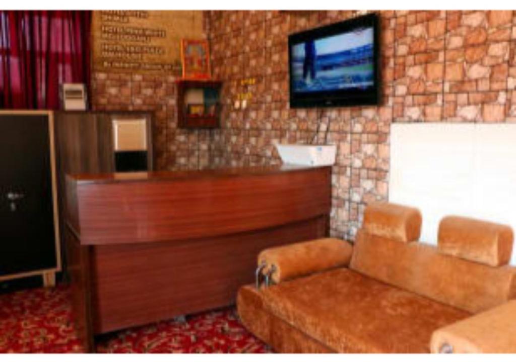 a living room with a flat screen tv on a brick wall at Inderlok Hotel in Chandīgarh