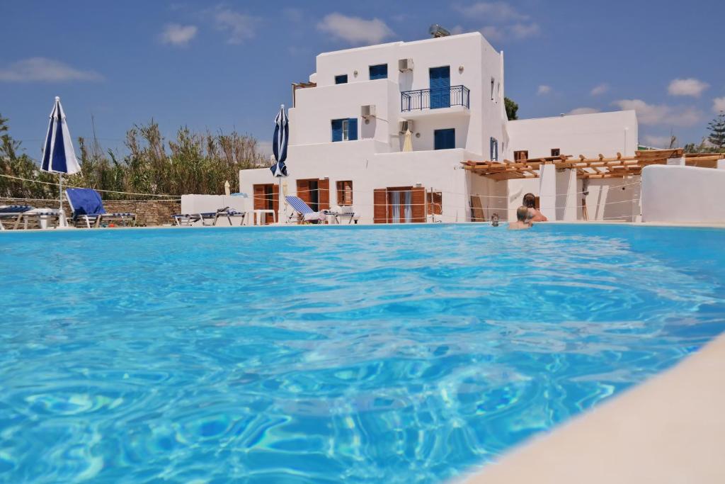 una mujer parada en una piscina frente a una casa en Katerina Suites en Naxos