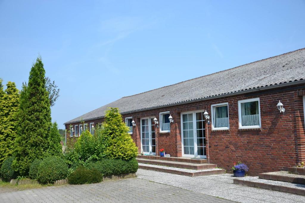 a red brick building with trees in front of it at Ferien- und Reiterparadies Voßhörnerhof in Neuschoo