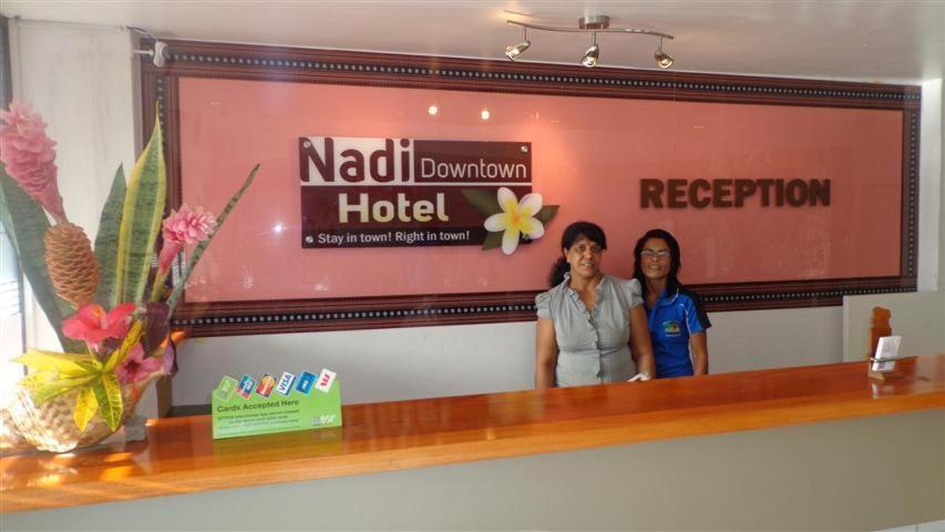 Due donne in piedi davanti a un cartello in un hotel di Nadi Downtown Hotel a Nadi