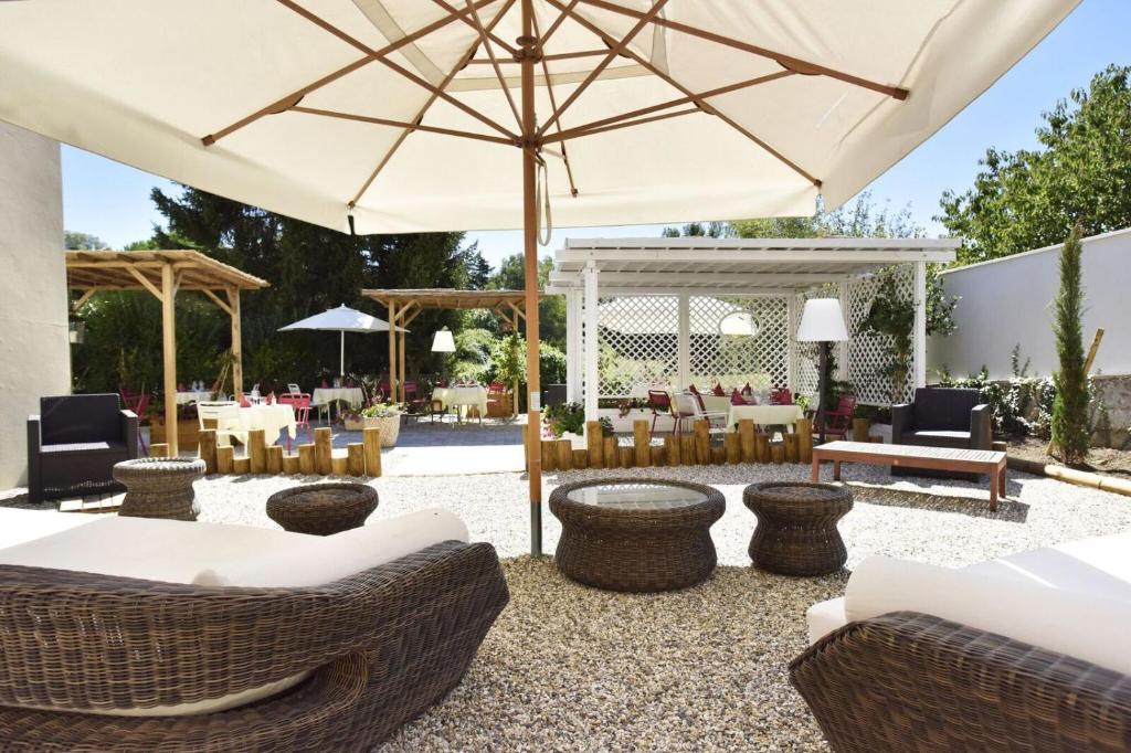 un patio con tavoli, sedie e ombrellone di Logis Hôtel-Restaurant Le Relais a Hauterives