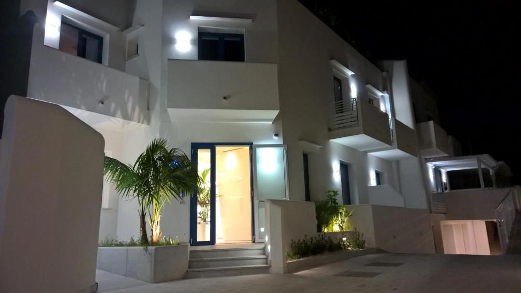 a white building with a door and a palm tree at Hermes Hotel in San Vito lo Capo