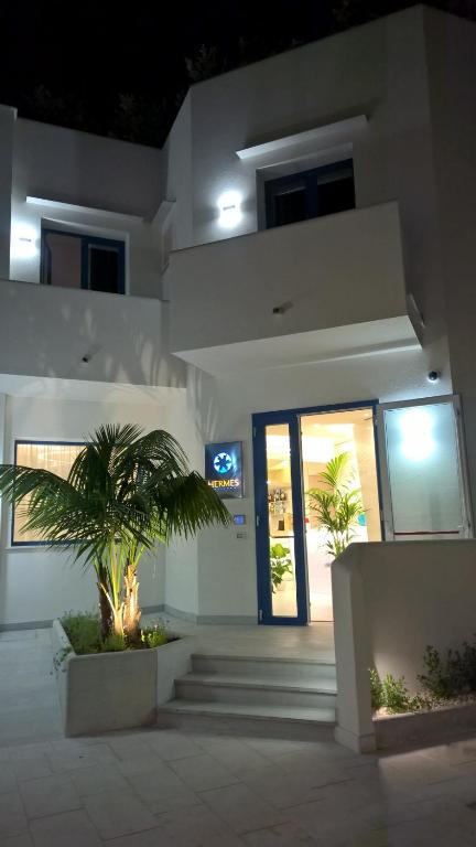 a building with a palm tree in front of a door at Hermes Hotel in San Vito lo Capo