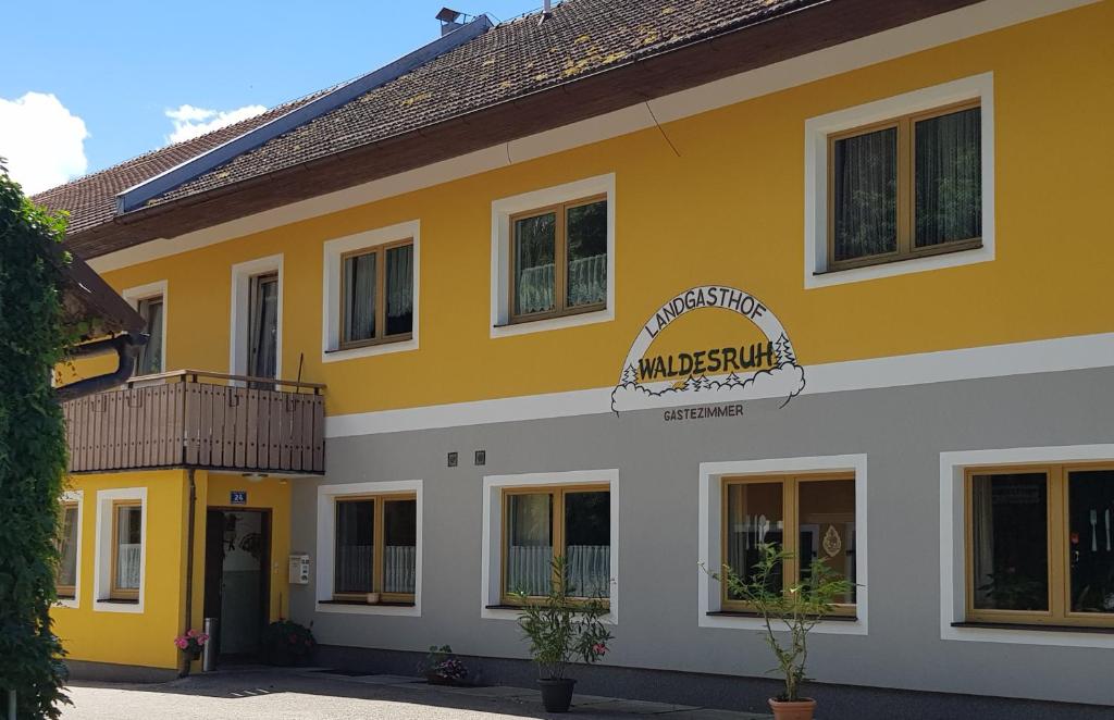 un bâtiment jaune et blanc avec un panneau sur lequel figure un panneau dans l'établissement Landgasthof Waldesruh, à Gallspach