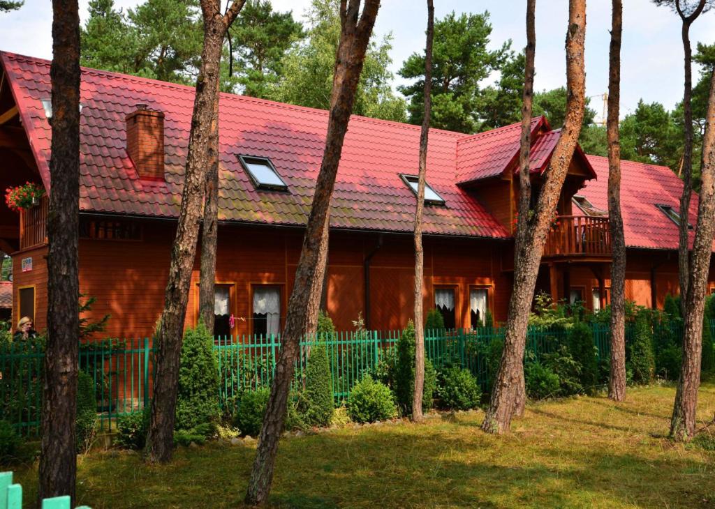 a house with a red roof and a group of trees at Morska Przystan in Dziwnówek