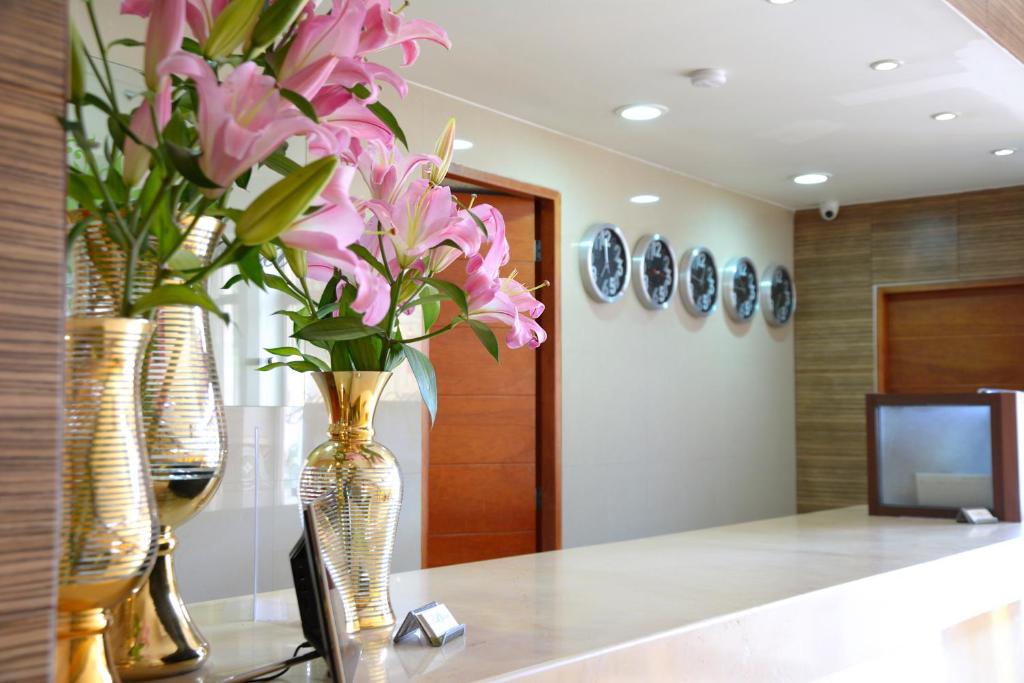 a lobby with two vases with pink flowers on a counter at Hotel Victoria in Lagos de Moreno