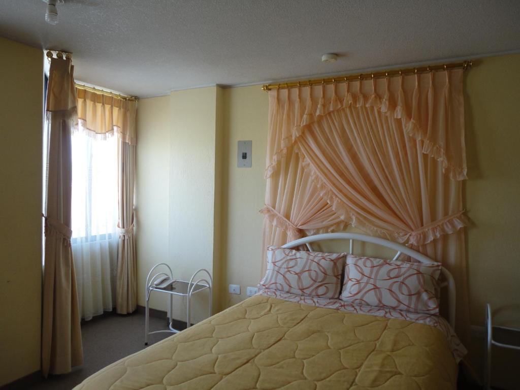 een slaapkamer met een hemelbed en een raam bij Hostal El Sol de Cayambe in Cayambe