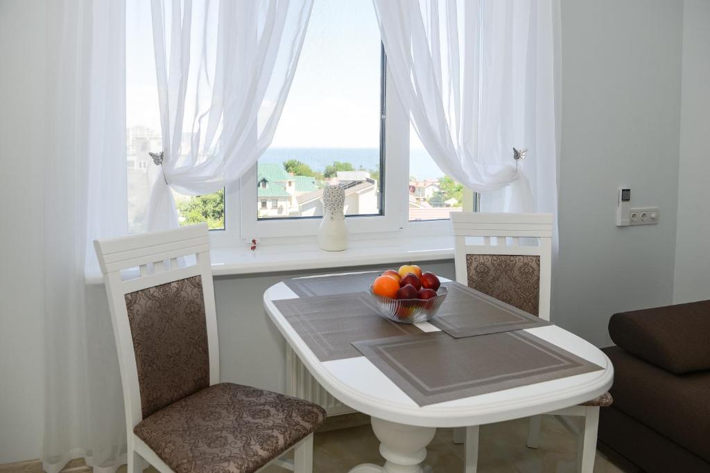 a white table with a bowl of fruit on it in front of a window at Sea View Odessa in Odesa