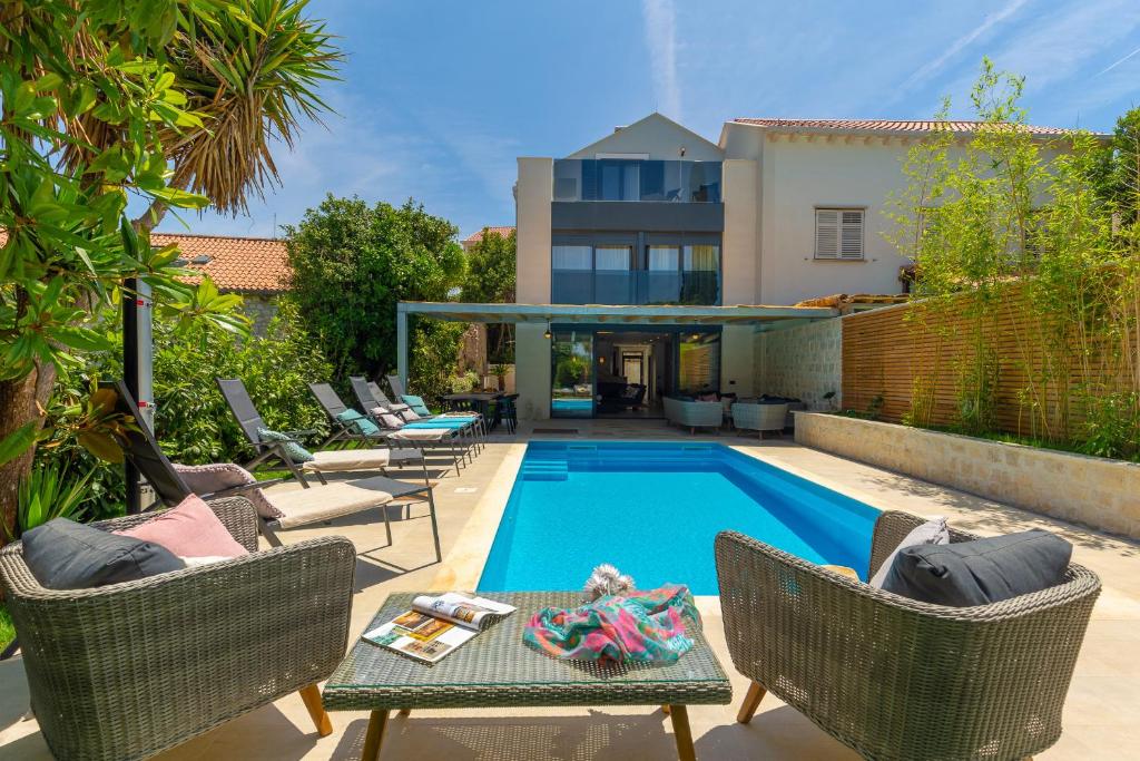 a swimming pool with chairs and a table next to a house at Villa Hedera II in Dubrovnik