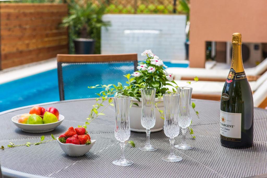 una mesa con una botella de vino y un bol de fruta en Apartmani Ana en Kaštela