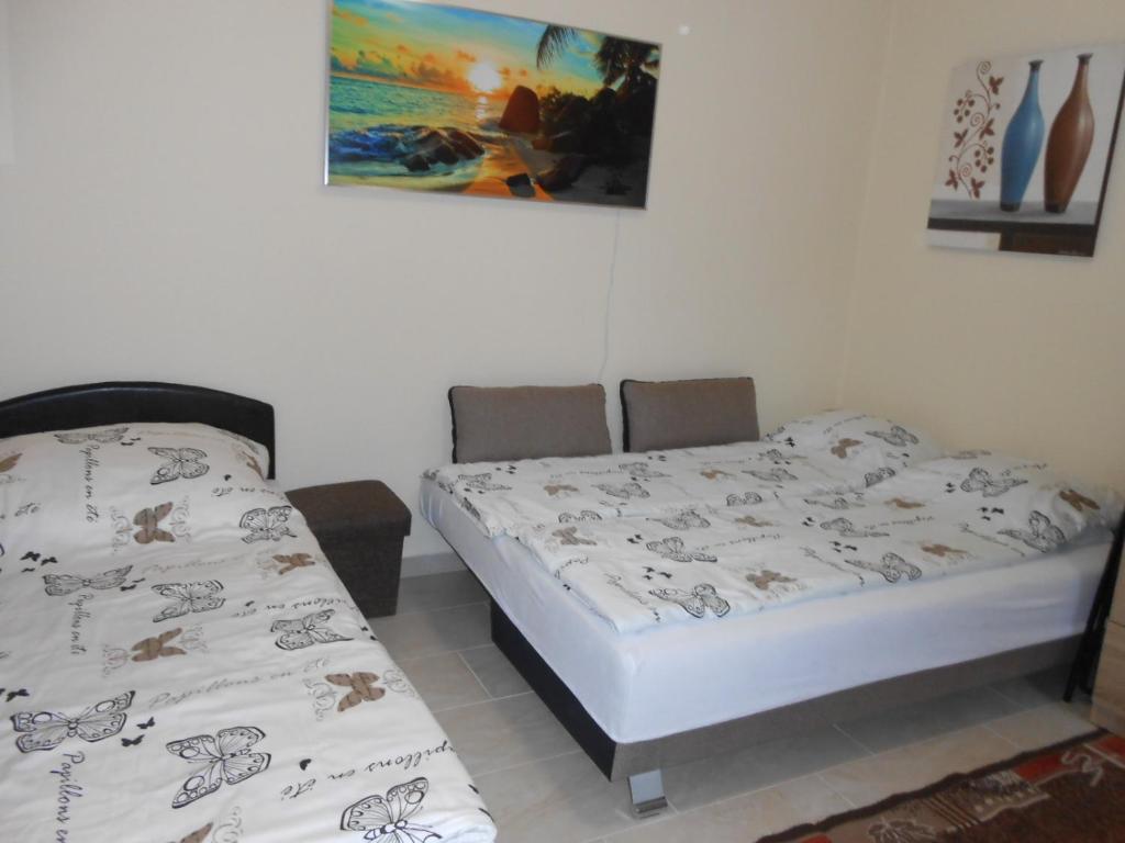 ハイドゥソボスローにあるZsóka apartmanのベッドルーム1室(ベッド2台付)が備わります。壁には絵画が飾られています。