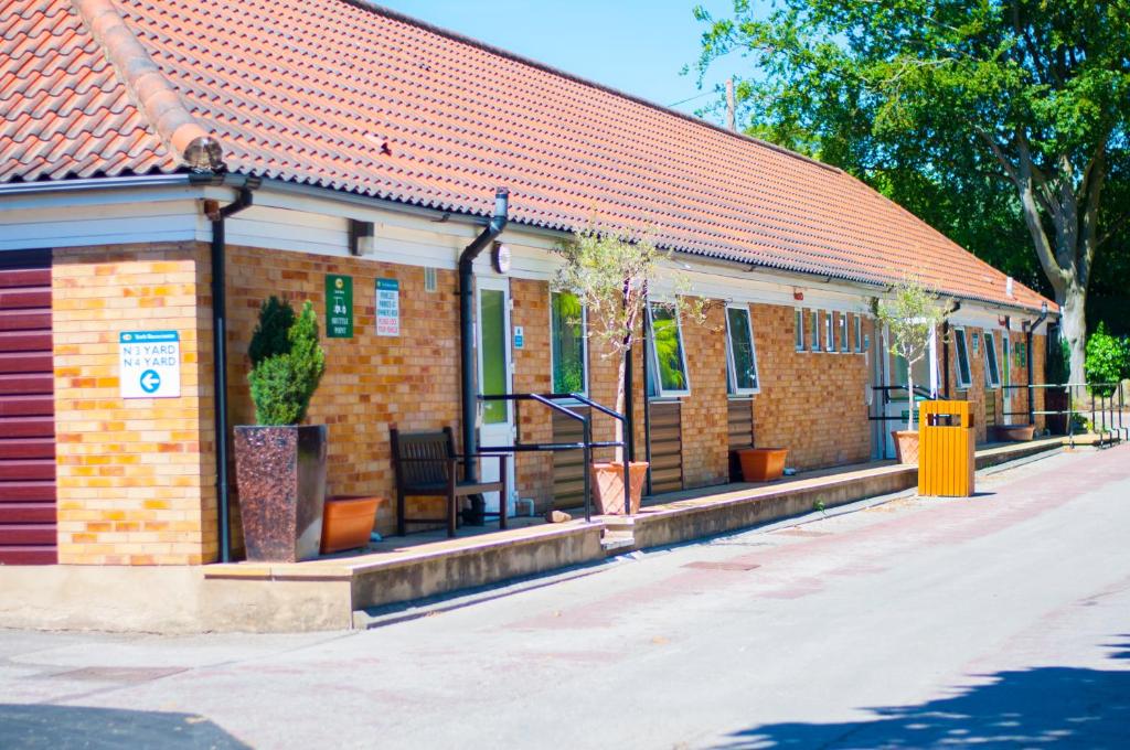 a brick building with trees in front of it at Stableside Hostel at York Racecourse in York