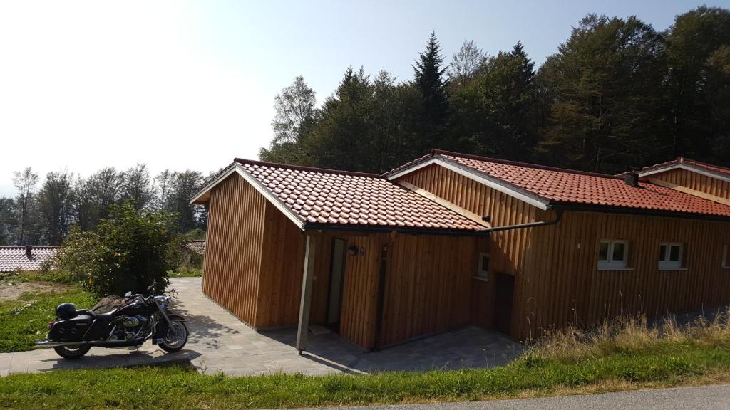 a motorcycle parked in front of a wooden building at Ferienbungalow Sonnenwald Bayerischer Wald in Schöfweg