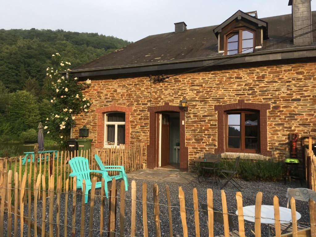 una casa de ladrillo con 2 sillas verdes y una valla en Gite la Truite a Mouzaive, en Vresse-sur-Semois