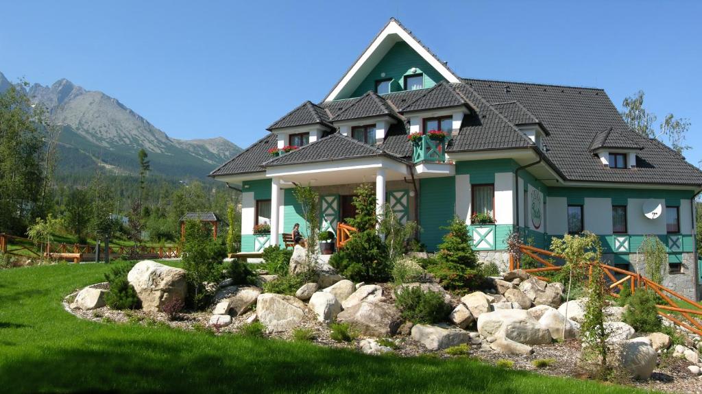 una casa verde con rocas delante de ella en Penzión Paula en Tatranská Lomnica